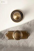 Solid brass single-hole cabinet handle with round knob and scalloped backplate, antique finish