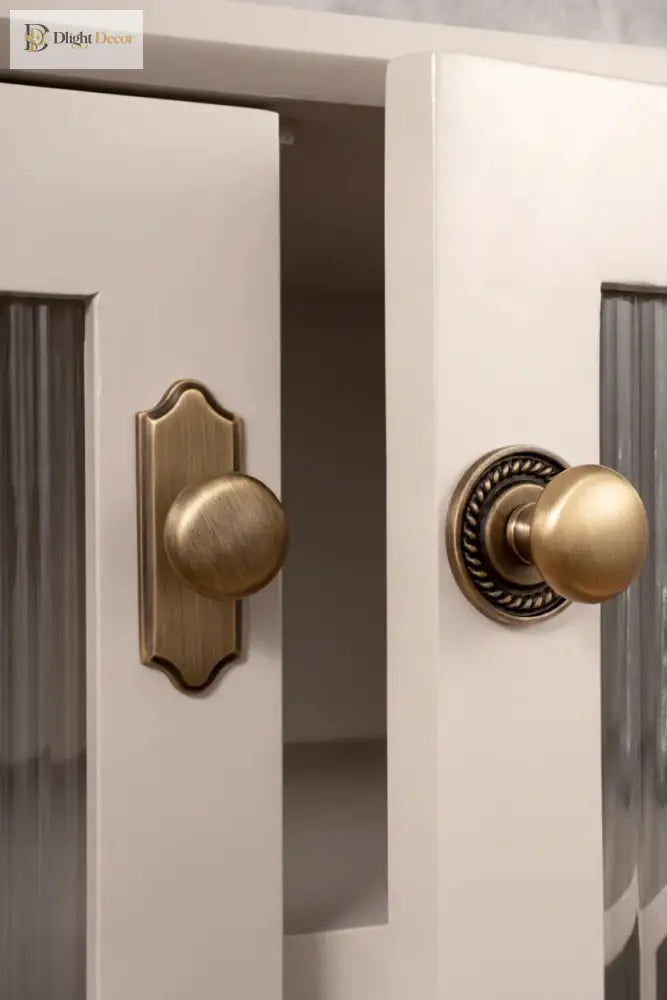 Single-hole cabinet handle mounted on door panel: round knob with ornate backplate, solid brass