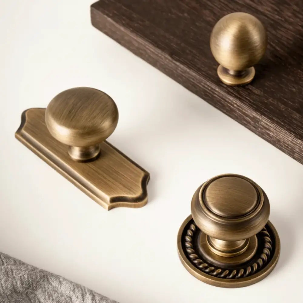 Antique single-hole cabinet handle with round knob and matching backplate, solid brass
