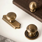 Antique single-hole cabinet handle with round knob and matching backplate, solid brass