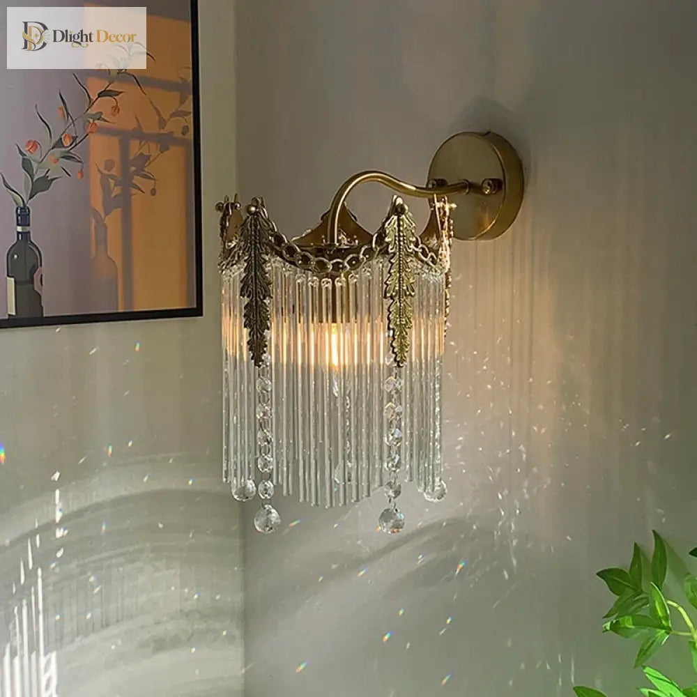 Gold crystal wall sconce with hanging crystal strands and lit bulbs behind