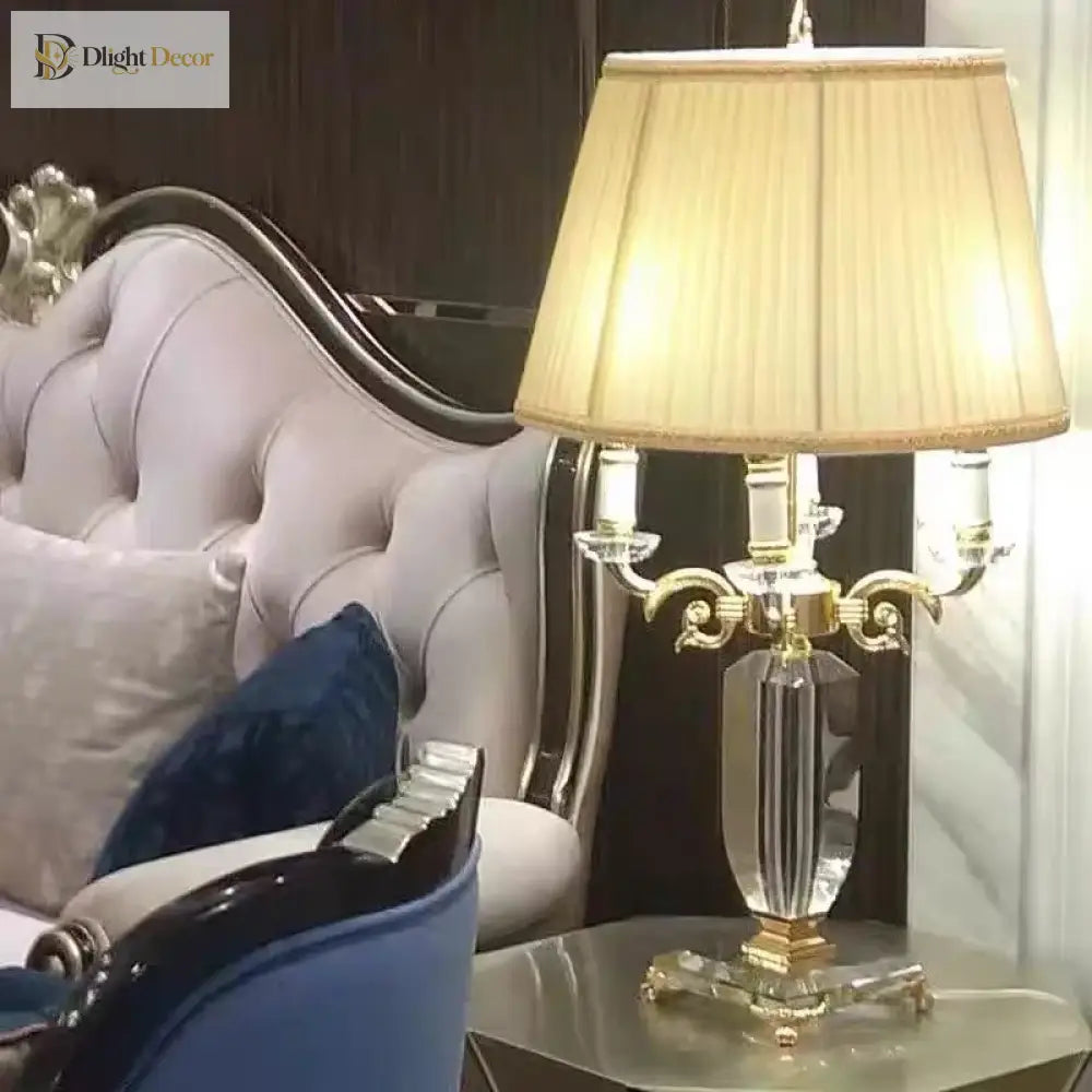 Gold and clear crystal table lamp with pleated white shade and faceted column base.