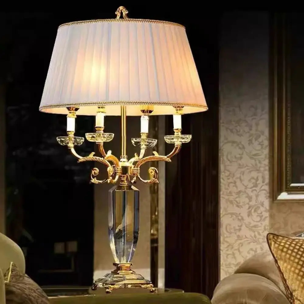 Gold crystal table lamp with pleated white shade and ornate candelabra base.