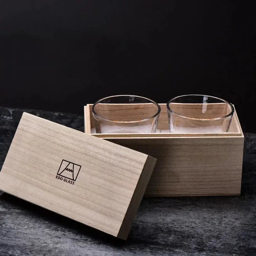 Two clear whiskey glasses in a light wood presentation box, front view