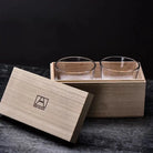 Two clear whiskey glasses in a light wood presentation box, front view